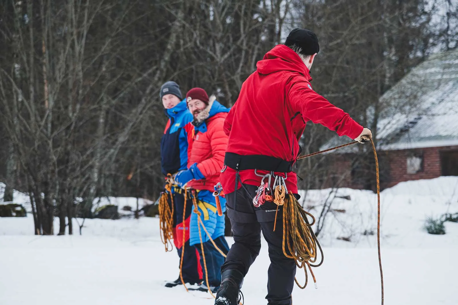 Retkikunnan jäsenet harjoittelevat köysien ja valjaiden käyttöä lumisella pihalla